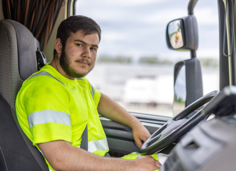 Ung man som sitter bakom ratten i en lastbil.